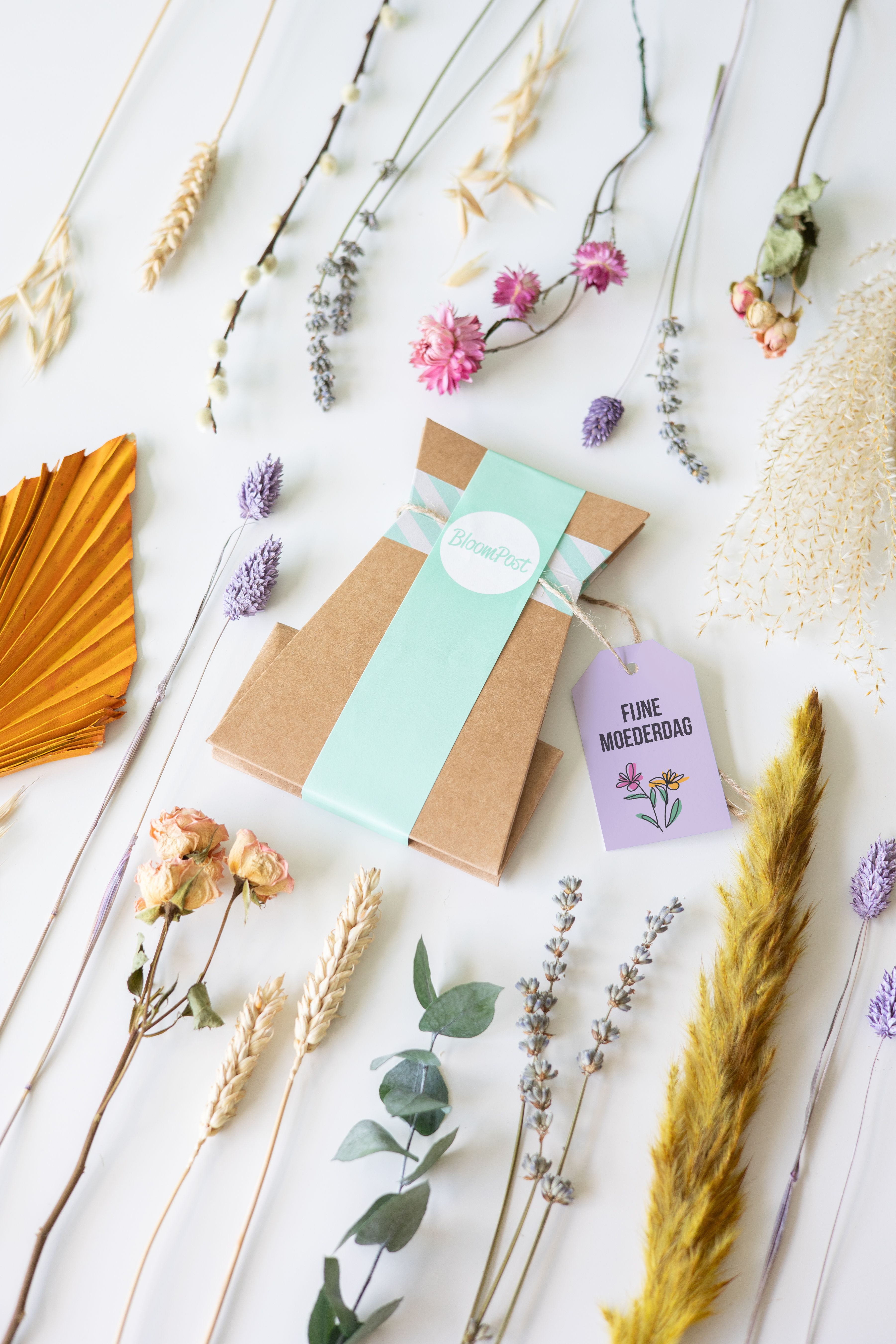 Brievenbuspakketje met droogbloemen in verschillende pastel tinten