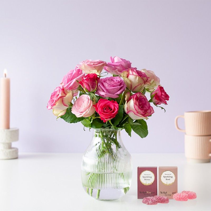 Brievenbuspakketje met verschillende tinten roze rozen en twee doosjes winegums