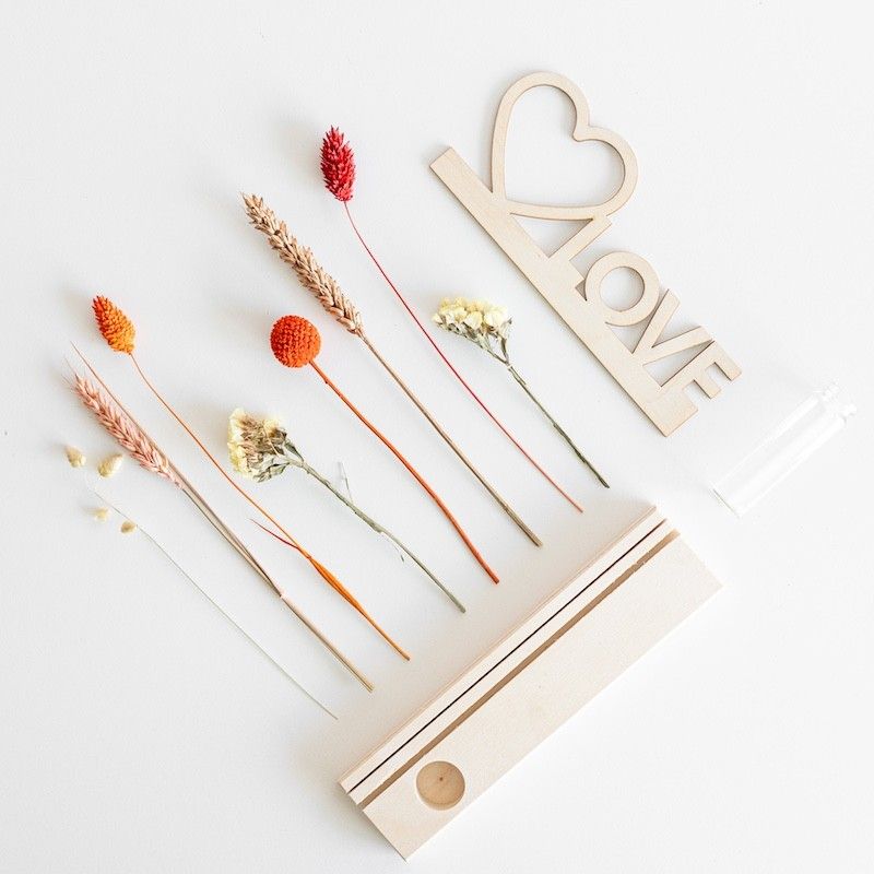 Brievenbuspakketje met houten plankje, houten plank met hart en love tekst en een vaasje met naturel en oranje droogbloemen
