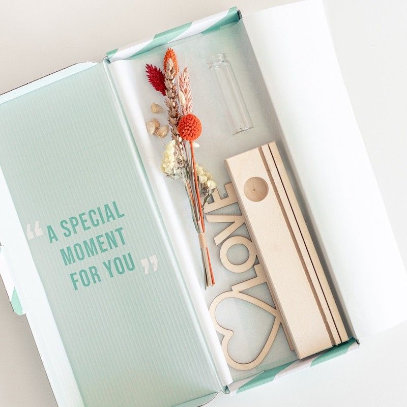 Brievenbuspakketje met houten plankje, houten plank met hart en love tekst en een vaasje met naturel en oranje droogbloemen