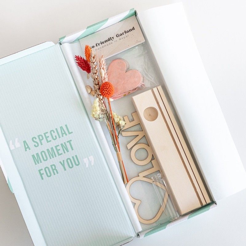 Brievenbuspakketje met houten plankje, houten plank met hart en love tekst en een vaasje met naturel en oranje droogbloemen