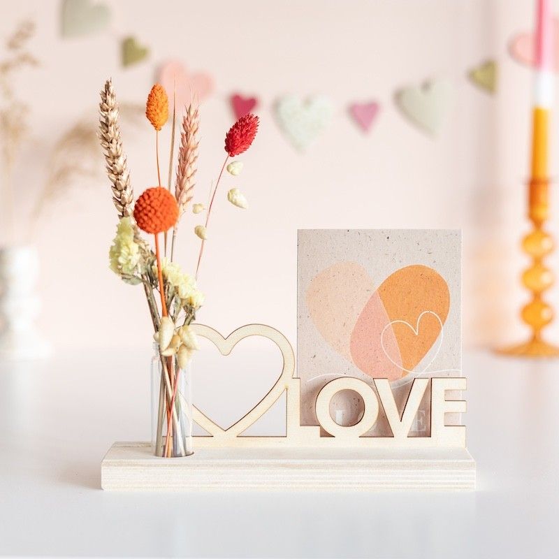 Brievenbuspakketje met houten plankje, houten plank met hart en love tekst en een vaasje met naturel en oranje droogbloemen
