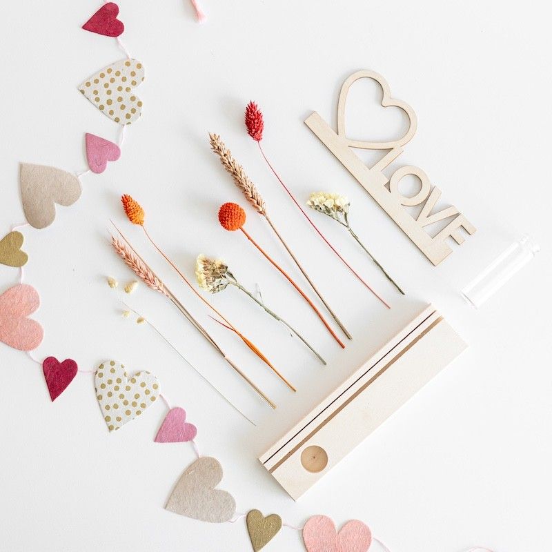 Brievenbuspakketje met houten plankje, houten plank met hart en love tekst en een vaasje met naturel en oranje droogbloemen