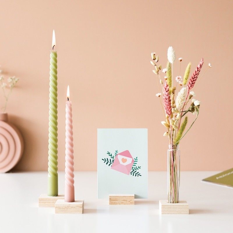 Twee gedraaide kaarsen (groen en roze), een vaasje droogbloemen en wenskaart in houten blokjes als standaard