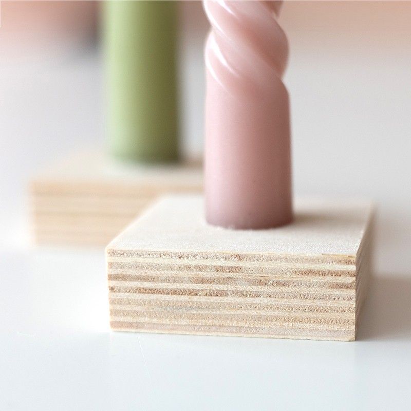 Twee gedraaide kaarsen (groen en roze), een vaasje droogbloemen en wenskaart in houten blokjes als standaard