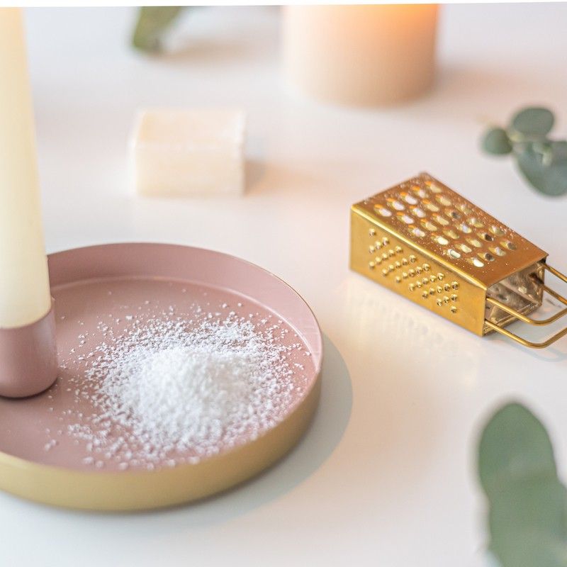 Roze goud schaaltje met een kaars en een amberblokje met daarnaast een gouden rasp