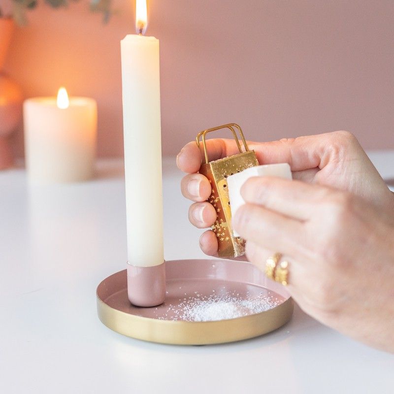 Roze goud schaaltje met een kaars en een amberblokje met daarnaast een gouden rasp