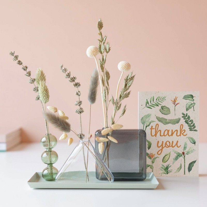 Drie verschillende vaasjes met droogbloemen op een plateau met een thank you wenskaart ernaast