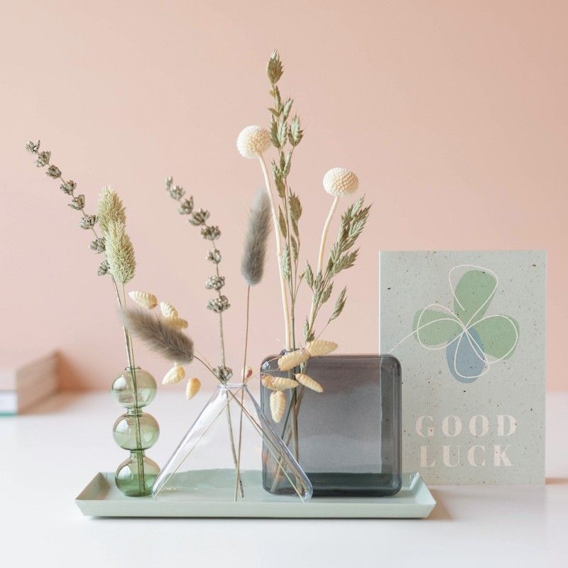 Verschillende vaasjes op een plateau met naturel droogbloemen en een good luck wenskaart ernaast