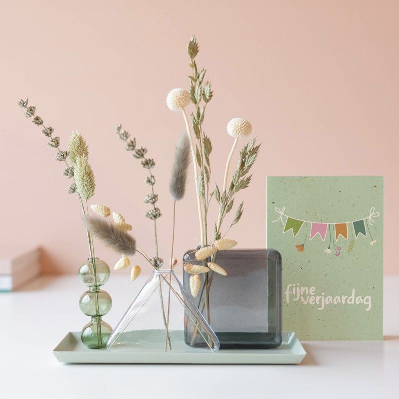 Drie verschillende vaasjes met droogbloemen op een plateau met een fijne verjaardag wenskaart ernaast