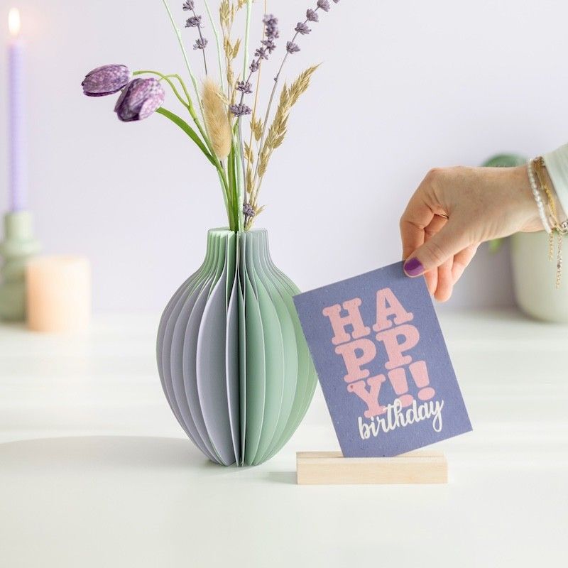 pastel groen en paarse vouwvaas met paarse en naturel droogbloemen en een houten plankje ernaast waar een kaart in gezet kan worden