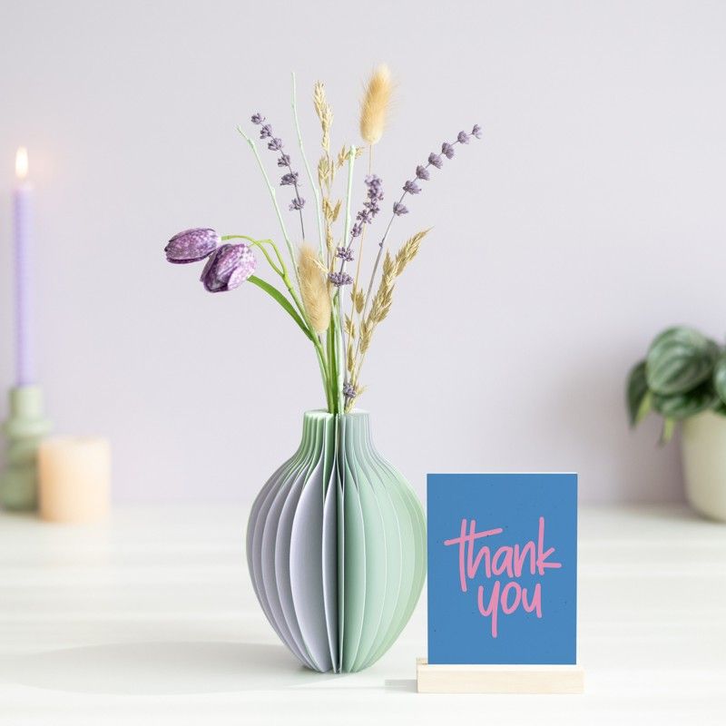 pastel groen en paarse vouwvaas met paarse en naturel droogbloemen en een houten plankje ernaast waar een kaart in gezet kan worden
