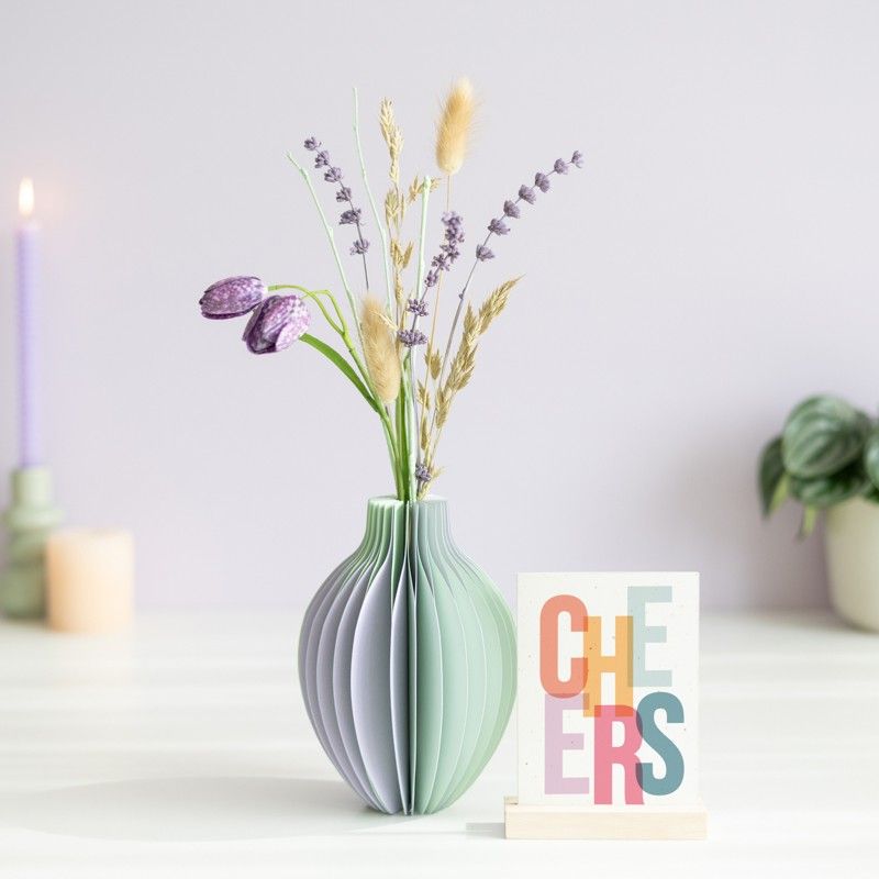 pastel groen en paarse vouwvaas met paarse en naturel droogbloemen en een houten plankje ernaast waar een kaart in gezet kan worden