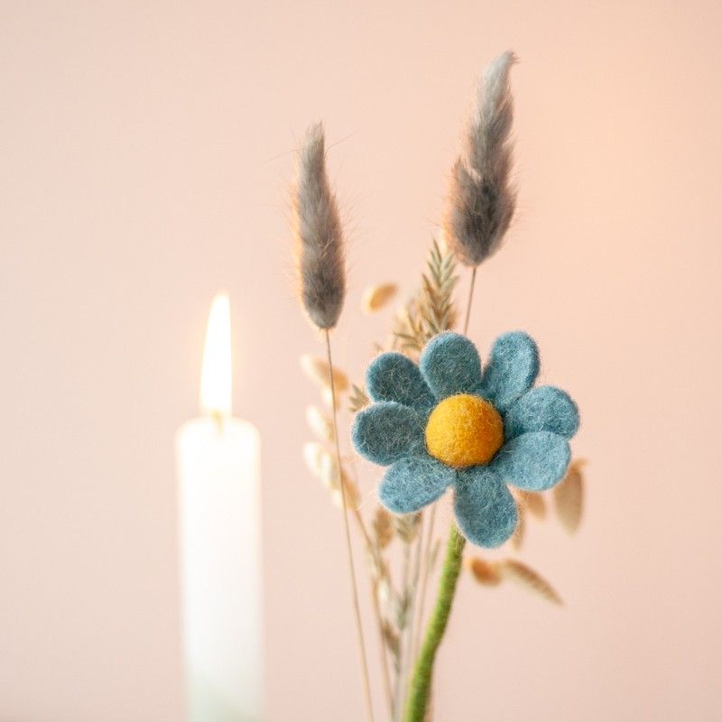 Brievenbuspakketje met wit groene kaars in een houten blokje met daarnaast een vaasje droogbloemen en vilten bloemen in een houten blokje