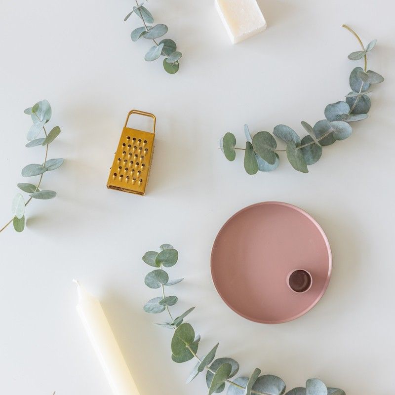 Roze goud schaaltje met een kaars en een amberblokje met daarnaast een gouden rasp