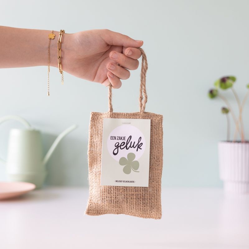 Zakje geluk van jute wordt vastgehouden in een hand, klaar om cadeau te geven.