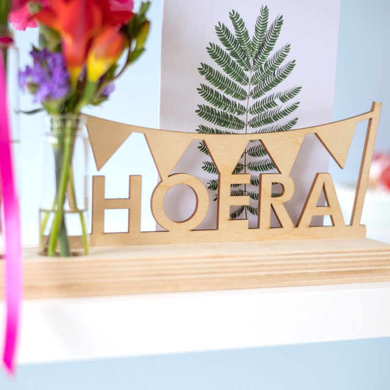 Brievenbuspakket met een houten plankje, houten hoera tekst en twee vaasjes met verse bloemen. Er is ruimte voor een wenskaart in de plank