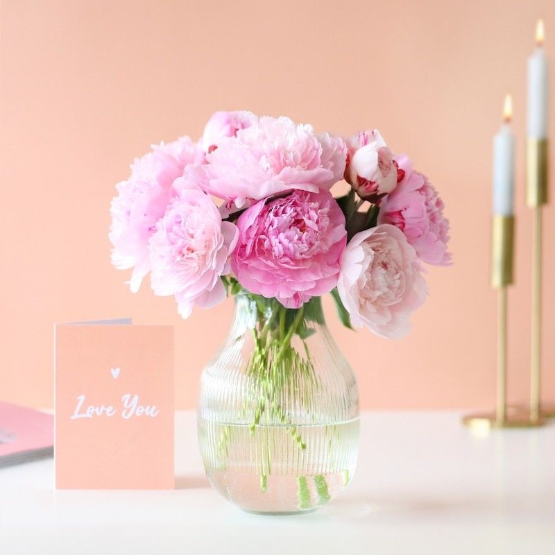 Roze pioenrozen in een glazen vaas