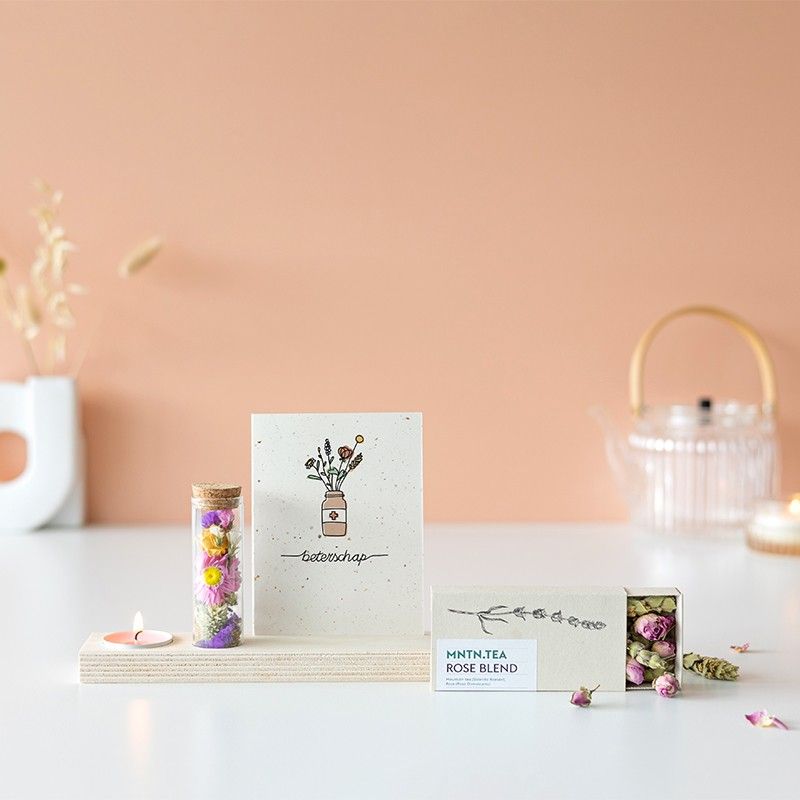 Houten plankje met kaarsje en buisje met droogbloemen. Er is ruimte voor een kaart in het plankje