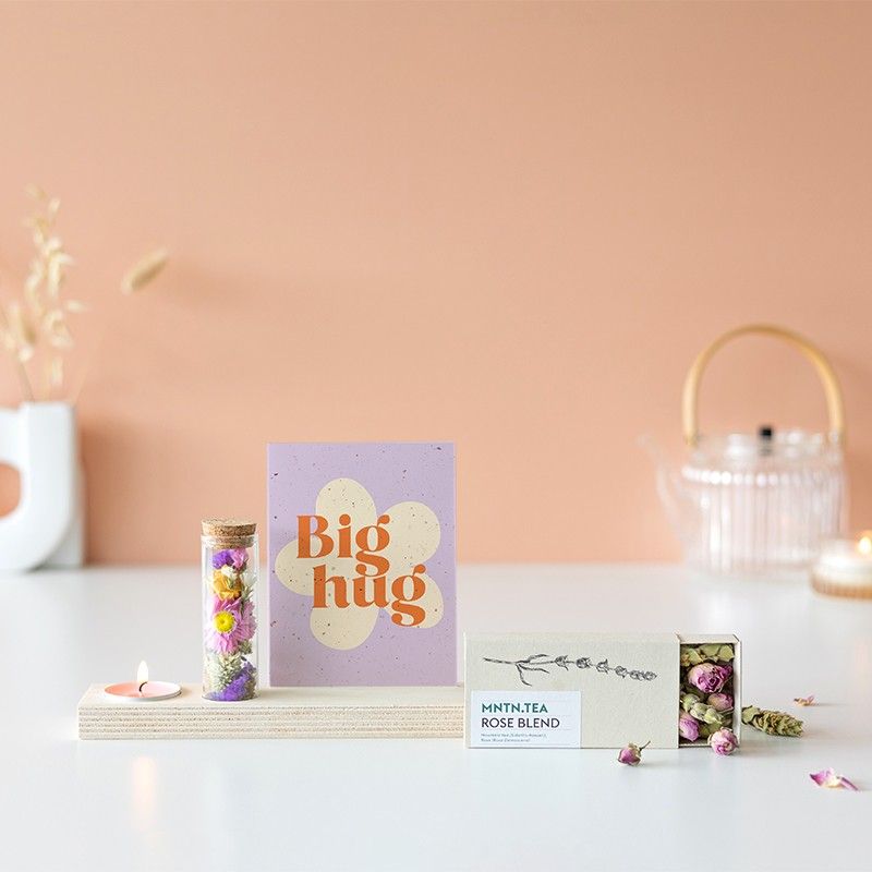 Houten plankje met kaarsje en buisje met droogbloemen. Er is ruimte voor een kaart in het plankje