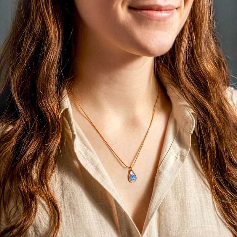 Vrouw draagt ketting met vergeet-mij-nietje hanger
