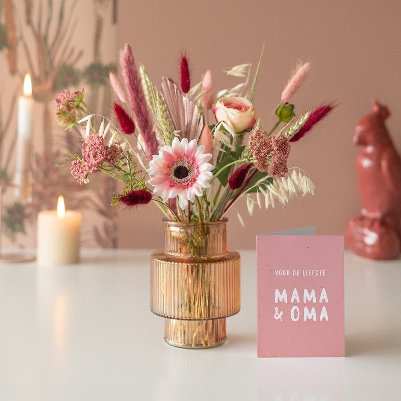 Mix van kunstzijden bloemen en droogbloemen boeket met roze bloemen in een transparante vaas met een mama en oma wenskaart