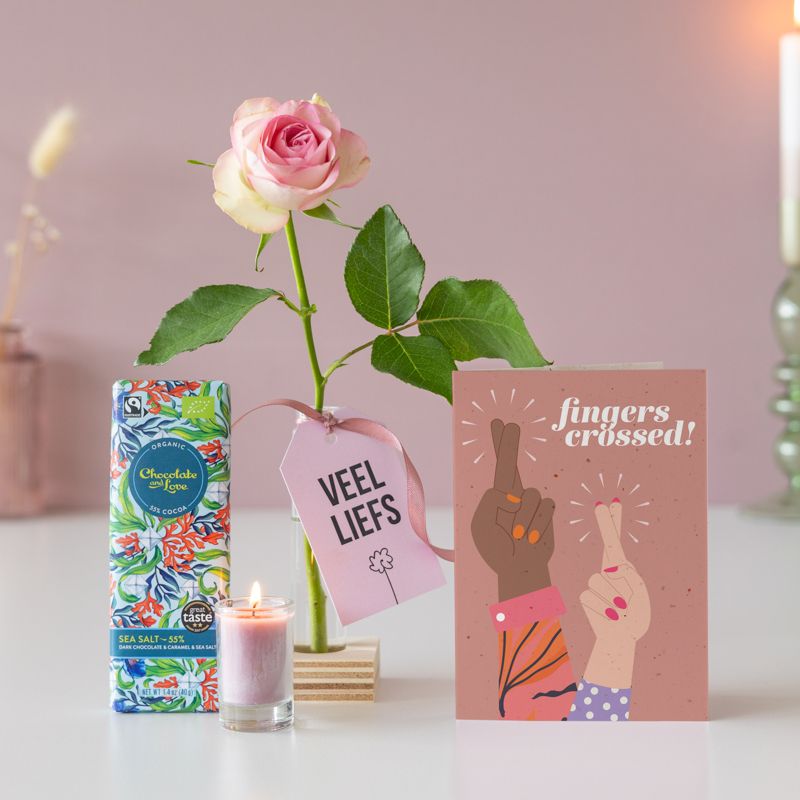 Brievenbus pakketje met roze roos in vaasje met een houten blokje eronder, daarnaast een chocolate and love puur zeezout reep en een roze mini kaars in glazen vaasje