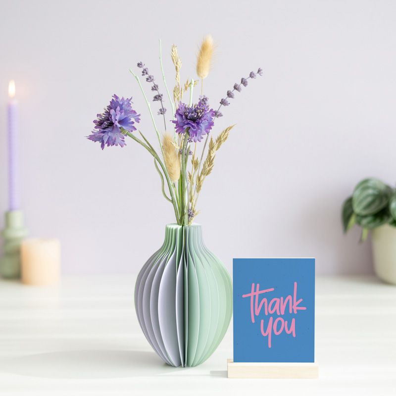 pastel groen en paarse vouwvaas met paarse en naturel droogbloemen en een houten plankje ernaast waar een kaart in gezet kan worden