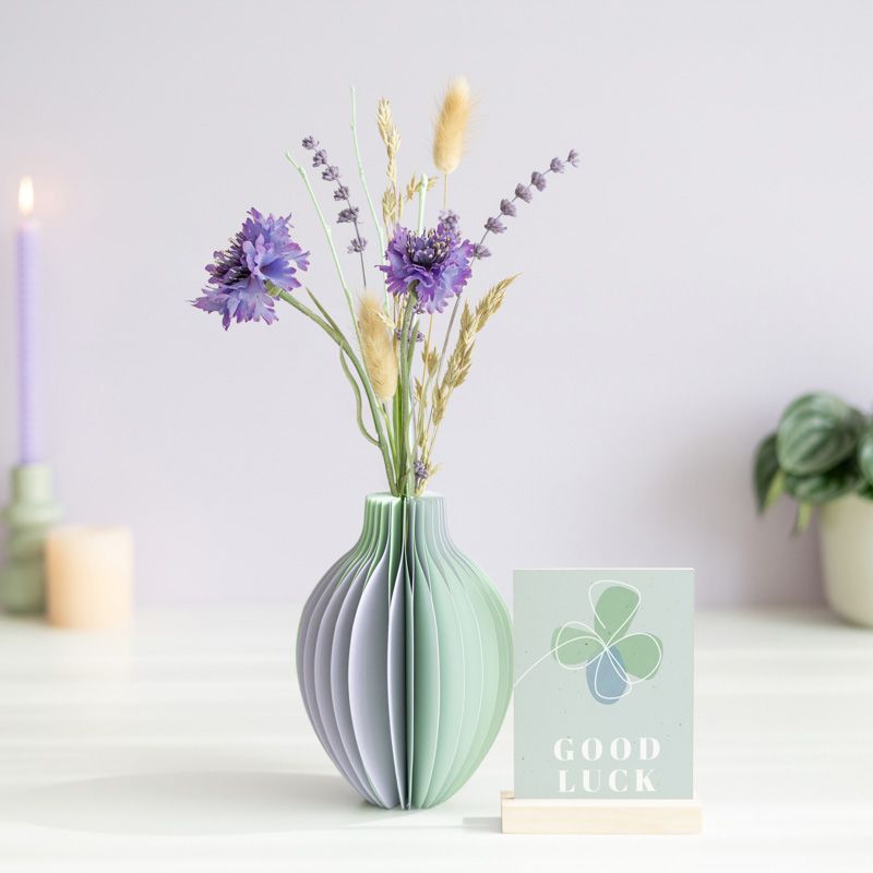 pastel groen en paarse vouwvaas met paarse en naturel droogbloemen en een houten plankje ernaast waar een kaart in gezet kan worden