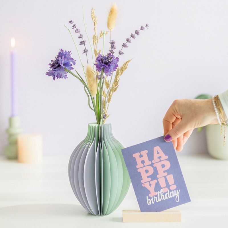 pastel groen en paarse vouwvaas met paarse en naturel droogbloemen en een houten plankje ernaast waar een kaart in gezet kan worden