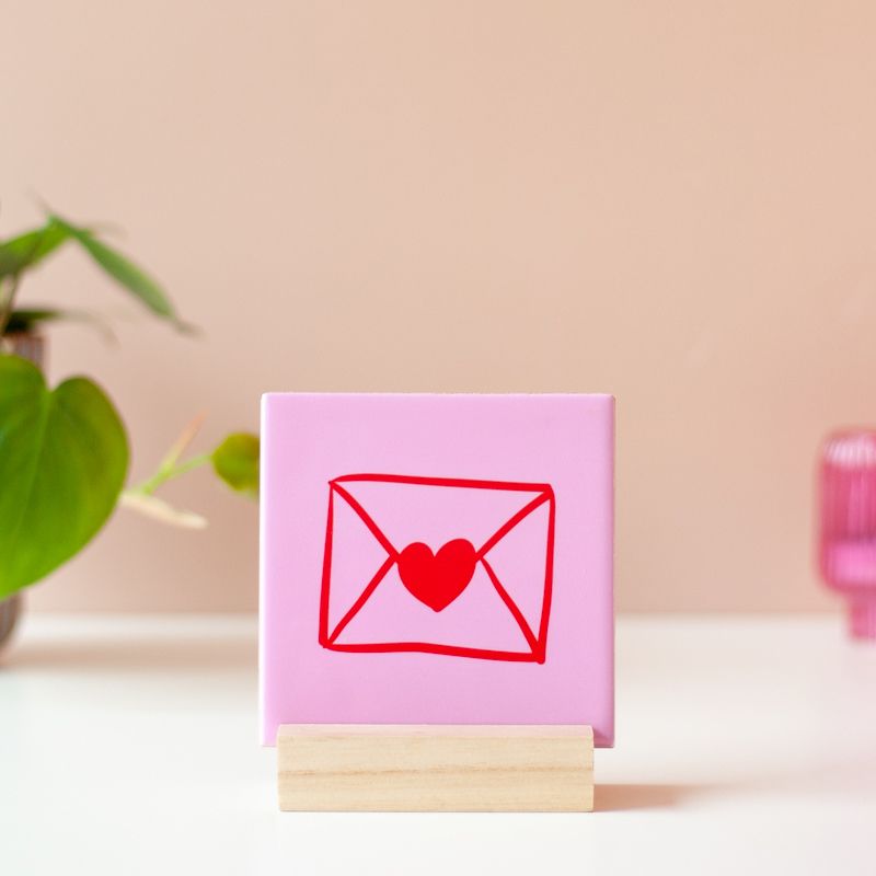 Roze tegeltje met een rood envelop met hartje erop in een houten houder