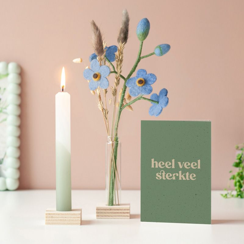 Lichtpuntje voor jou met blauwe vilten bloemen in een vaasje in houten blokje met daarnaast een wit groene kaars in houten blokje. Er staat een heel veel sterkte kaart naast