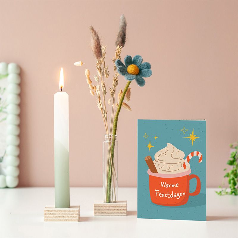 Brievenbuspakketje met wit groene kaars in een houten blokje met daarnaast een vaasje droogbloemen en vilten bloemen in een houten blokje