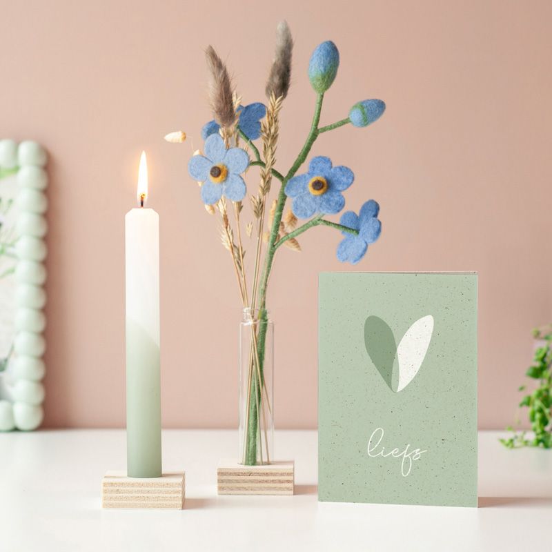 Brievenbuspakketje met wit groene kaars in een houten blokje met daarnaast een vaasje droogbloemen en vilten bloemen in een houten blokje