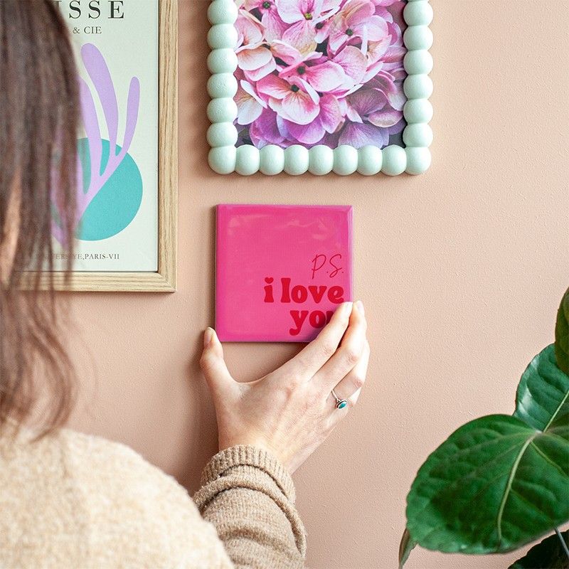 Tegeltje met ps i love you op een muur tussen schilderijen