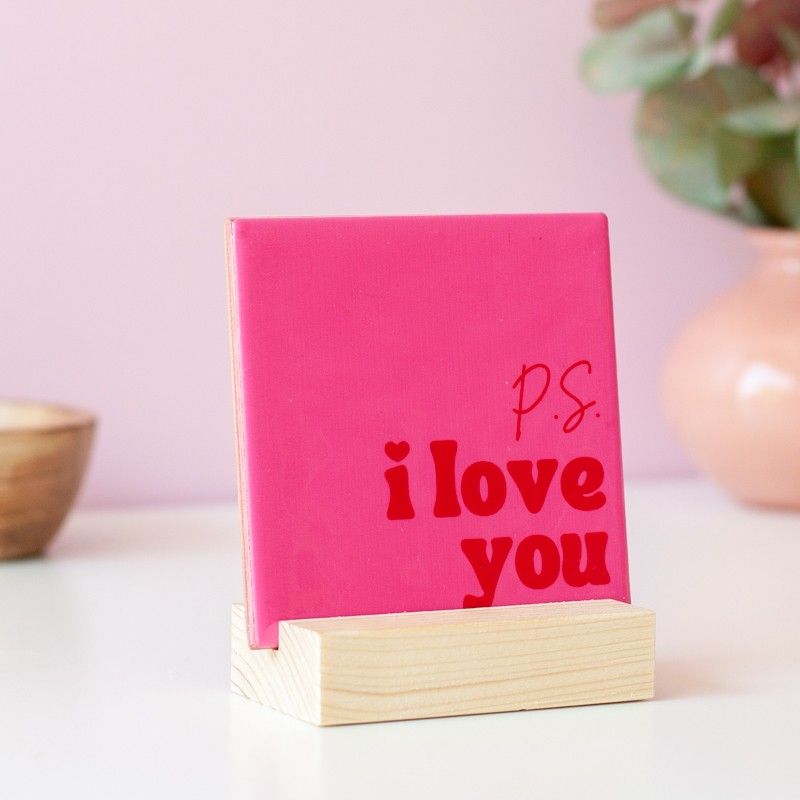 Roze tegeltje met P.S. I love you in rode letters in een houten standaard