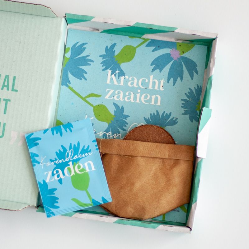 Blauw doosje met zaden van korenbloemen met de tekst kracht zaaien erop