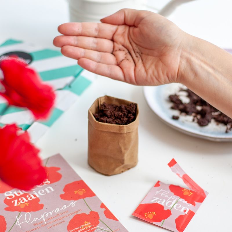 Rood paars doosje met klaproos zaden met daarbij de tekst succes zaaien