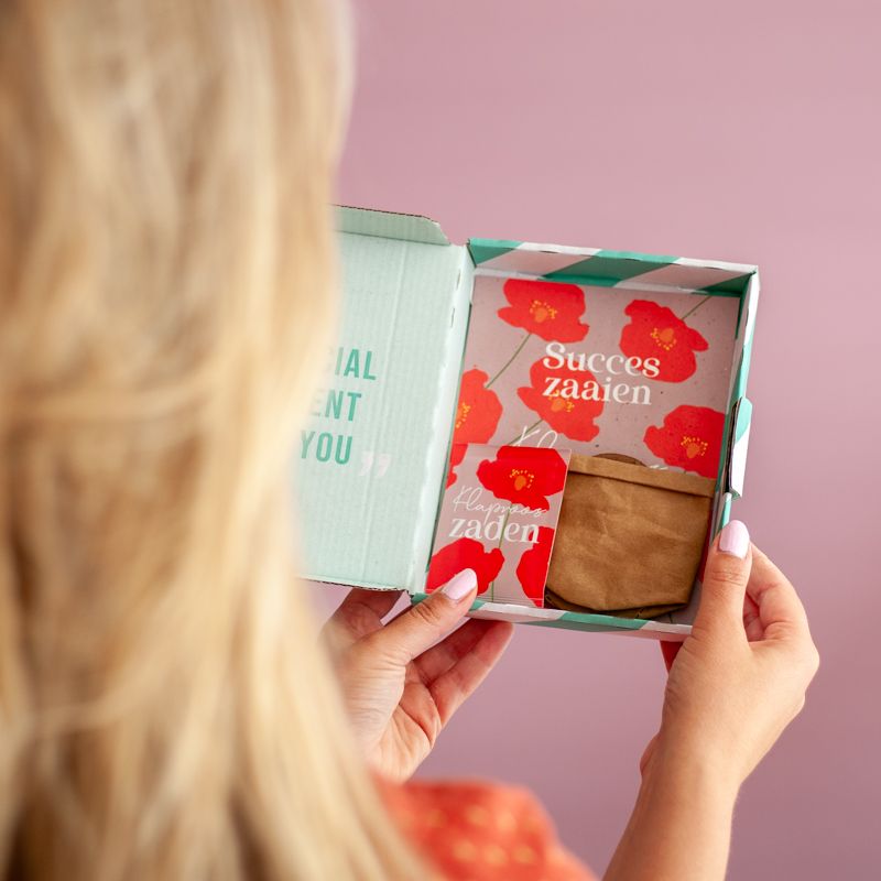 Rood paars doosje met klaproos zaden met daarbij de tekst succes zaaien