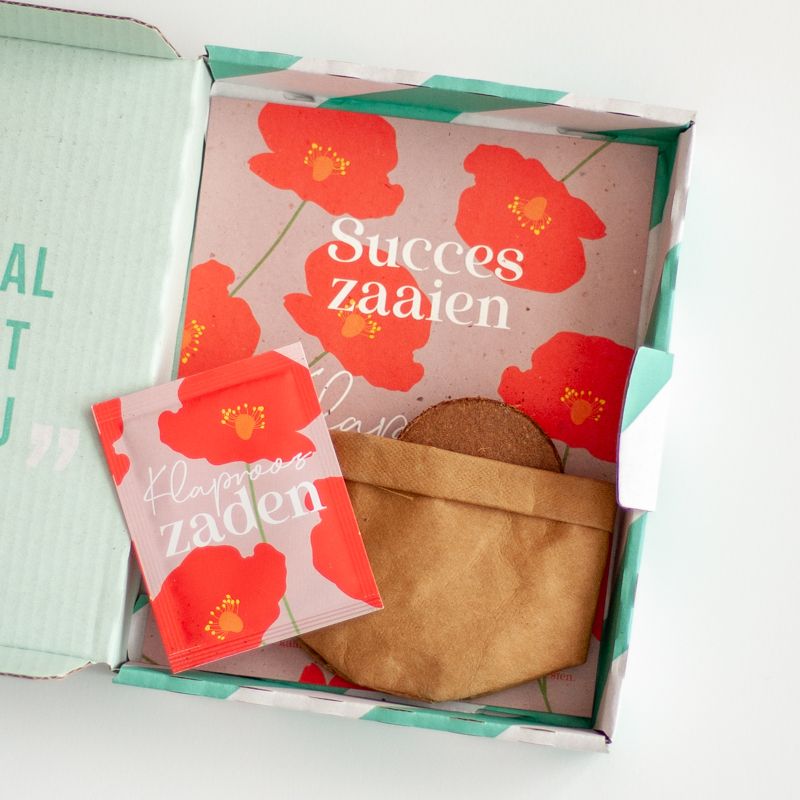 Rood paars doosje met klaproos zaden met daarbij de tekst succes zaaien