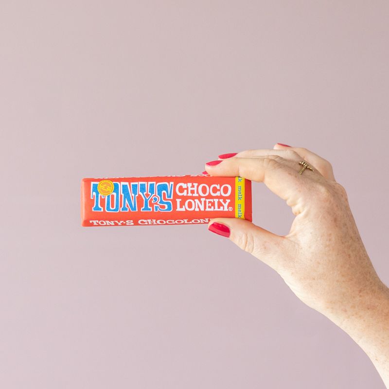 Roze roos in vaasje met label veel liefs en een melk chocoladereep van Tony Chocolonely ernaast