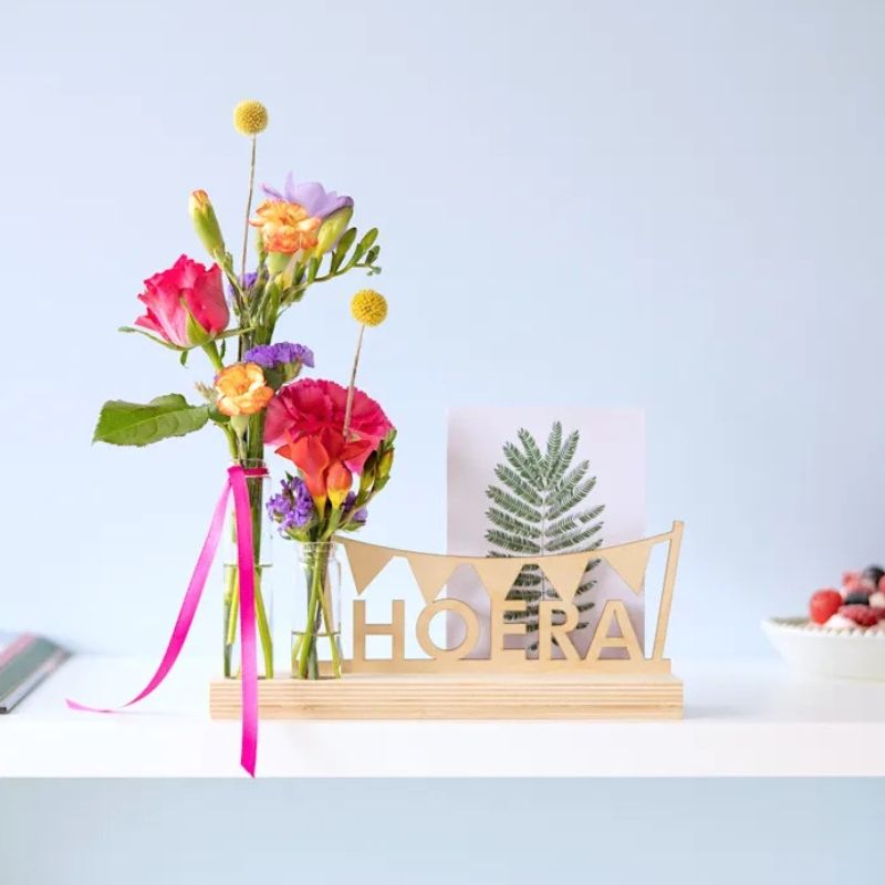 Brievenbuspakket met een houten plankje, houten hoera tekst en twee vaasjes met verse bloemen. Er is ruimte voor een wenskaart in de plank