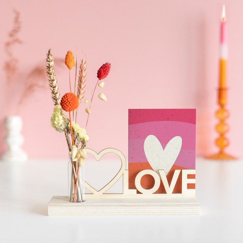 Brievenbuspakketje met houten plankje, houten plank met hart en love tekst en een vaasje met naturel en oranje droogbloemen