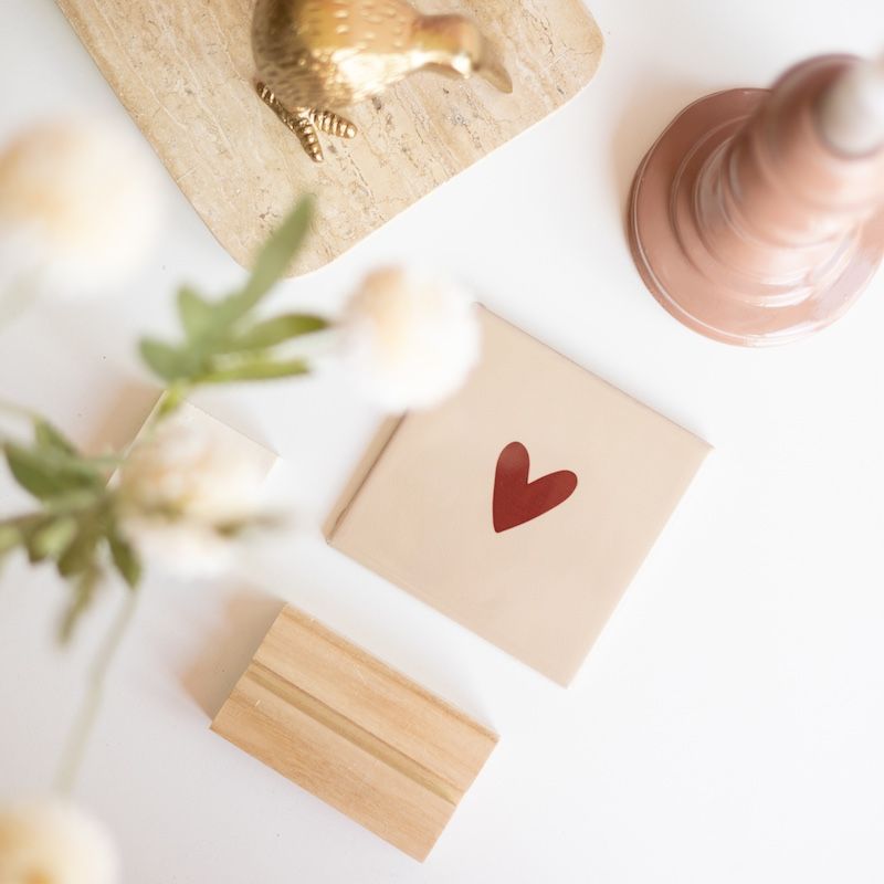 Beige tegel met bruin hartje erop in een houten houdertje