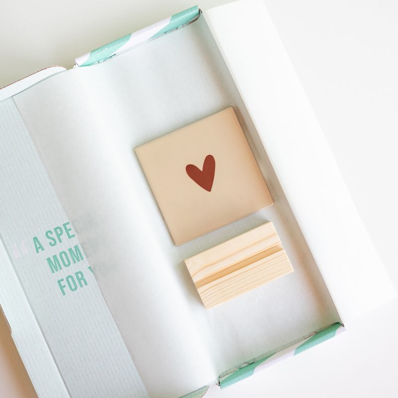 Beige tegel met bruin hartje erop in een houten houdertje