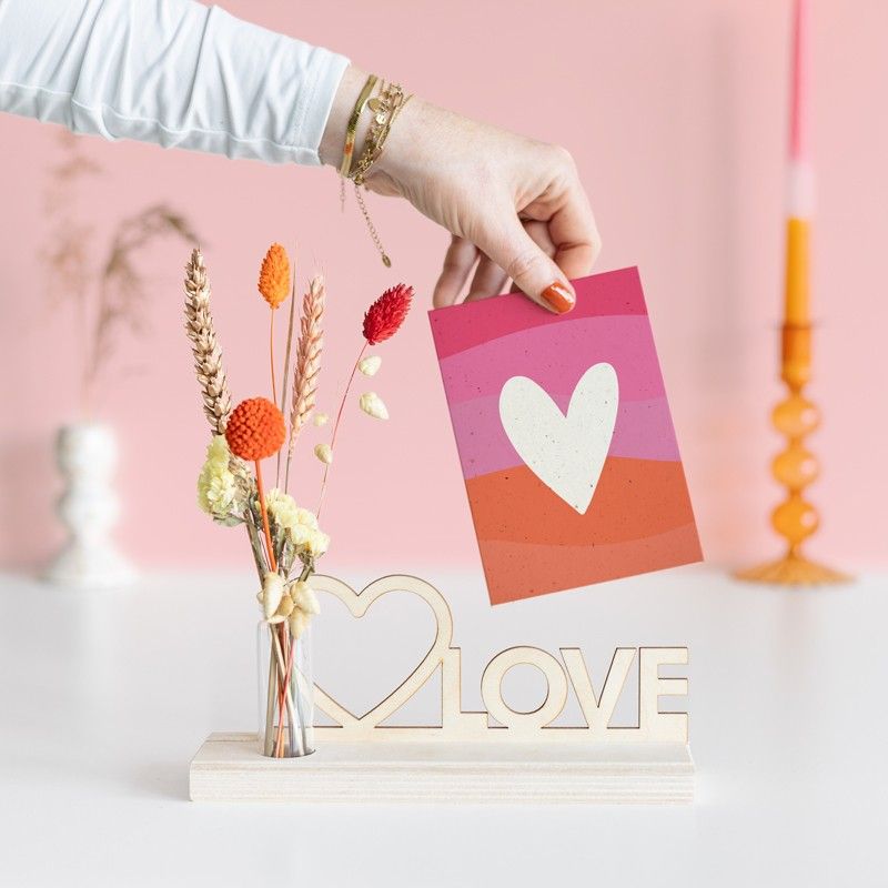 Brievenbuspakketje met houten plankje, houten plank met hart en love tekst en een vaasje met naturel en oranje droogbloemen